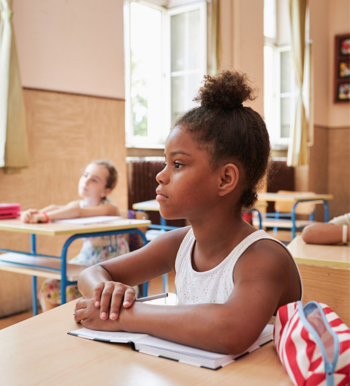 A young girl is paying close attention as she sits at a desk in a classroom